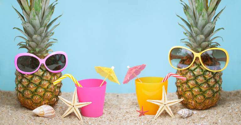 Twee ananassen met zonnebril op het strand aan het drinken