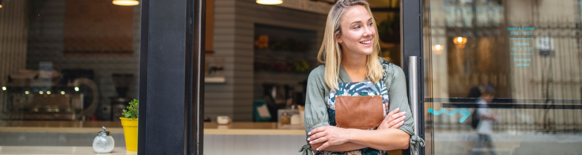 Jonge cafe eigenaar staat met haar armen gekruist bij de voordeur